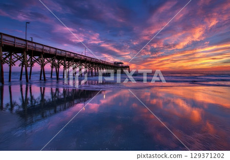 colorful sunrise over the beach with a pier. colorful sunrise over the beach with a pier. 129371202