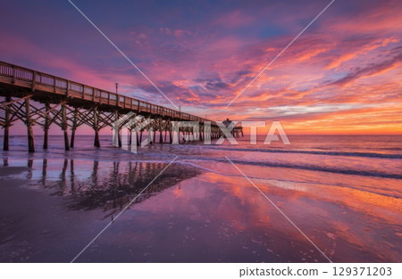 colorful sunrise over the beach with a pier. colorful sunrise over the beach with a pier. 129371203