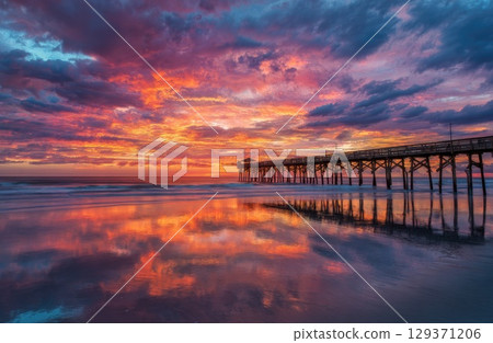colorful sunrise over the beach with a pier. colorful sunrise over the beach with a pier. 129371206