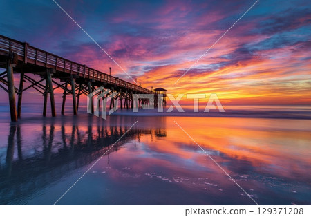 colorful sunrise over the beach with a pier. colorful sunrise over the beach with a pier. 129371208