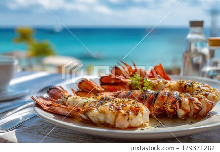 plate of fresh, grilled seafood with prawns and lobster on the beach in sunny Caribbean island 129371282