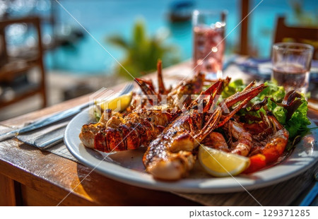 plate of fresh, grilled seafood with prawns and lobster on the beach in sunny Caribbean island 129371285