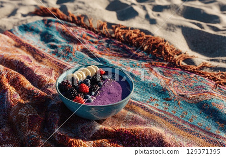 vibrant blue bowl filled with a purple smoothie, topped with banana slices and berries 129371395
