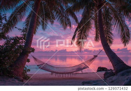 A cozy hammock between two palm trees on the beach at sunset, with a pink and purple sky. 129371432