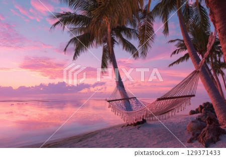 A cozy hammock between two palm trees on the beach at sunset, with a pink and purple sky. 129371433