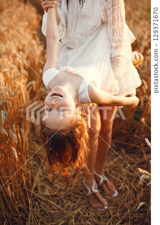 Family in a summer field. Sensual photo. Cute little girl. Woman in a white dress. 129371670