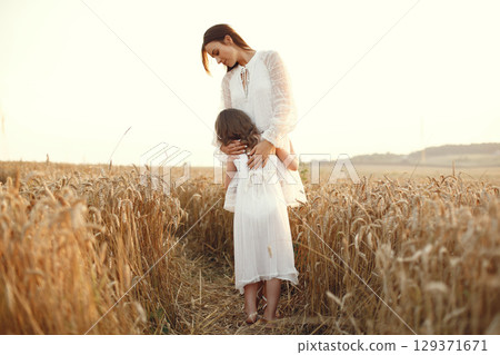 Family in a summer field. Sensual photo. Cute little girl. Woman in a white dress. 129371671