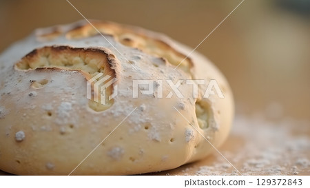 Close-up shot capturing a rustic loaf of sourdough bread with a golden-brown crust dusted with flour Close-up shot capturing a rustic loaf of sourdough bread with a golden-brown crust dusted with flour 129372843