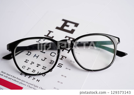 Glasses on eye exam chart to test eyesight accuracy of reading. Glasses on eye exam chart to test eyesight accuracy of reading. 129373143