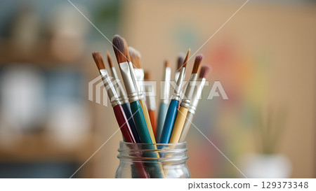 Assortment of colorful art paint brushes in a glass jar ready for artistic creation 129373348