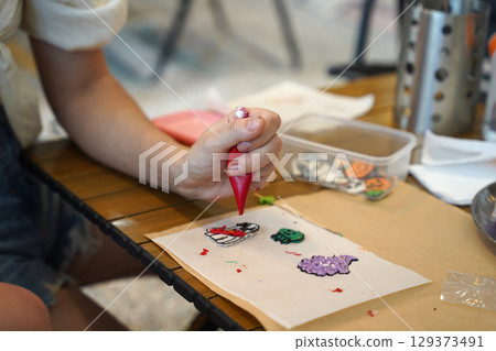 Mother and her daughter paint Halloween cookies  129373491
