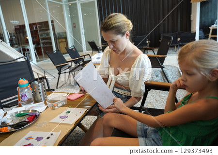 Mother and her daughter paint Halloween cookies  129373493