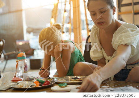 Mother and her daughter paint Halloween cookies  129373503