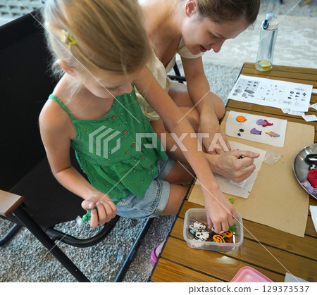 Mother and her daughter paint Halloween cookies Mother and her daughter paint Halloween cookies 129373537