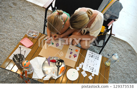 Mother and her daughter paint Halloween cookies Mother and her daughter paint Halloween cookies 129373538