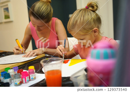 A mother and her young daughter engage in a colorful painting activity A mother and her young daughter engage in a colorful painting activity 129373540