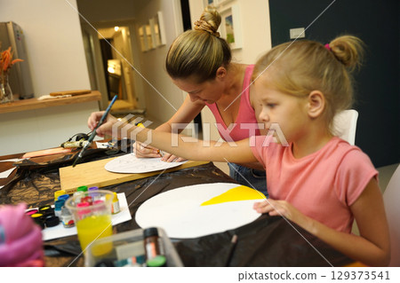 A mother and her young daughter engage in a colorful painting activity  129373541