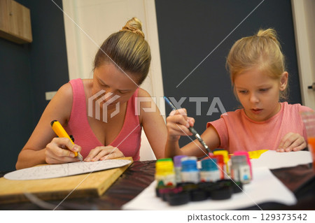 A mother and her young daughter engage in a colorful painting activity  129373542