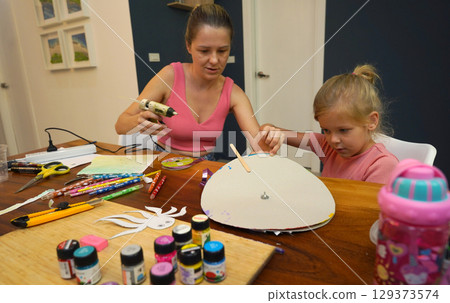 A mother and her young daughter engage in a colorful painting activity  129373574