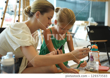 Mother and her daughter paint Halloween cookies Mother and her daughter paint Halloween cookies 129373583
