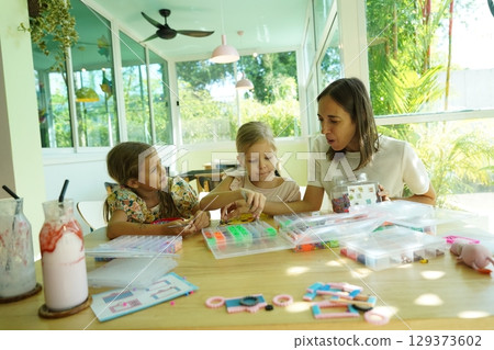 Teacher in workshop teched two girls how to assemble a thermo mosaic  129373602