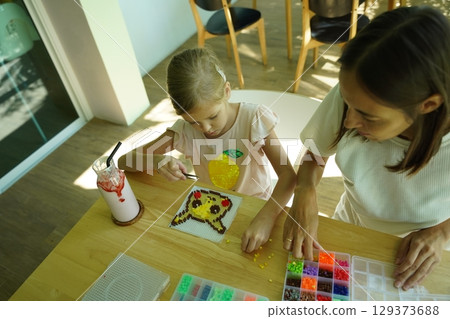 Teacher in workshop teched two girls how to assemble a thermo mosaic  129373688