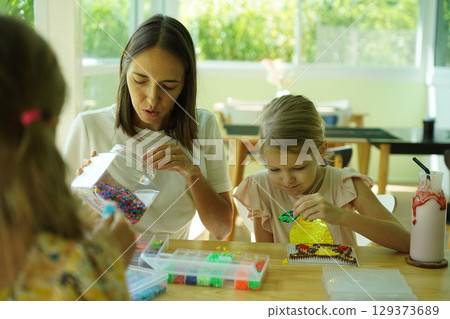 Teacher in workshop teched two girls how to assemble a thermo mosaic  129373689