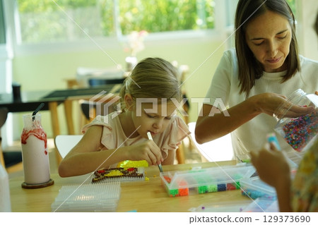 Teacher in workshop teched two girls how to assemble a thermo mosaic  129373690