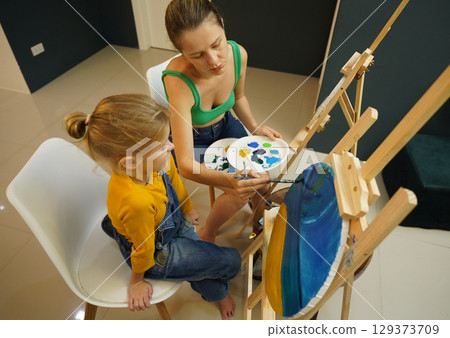 Teacher in workshop teched two girls how to assemble a thermo mosaic  129373709