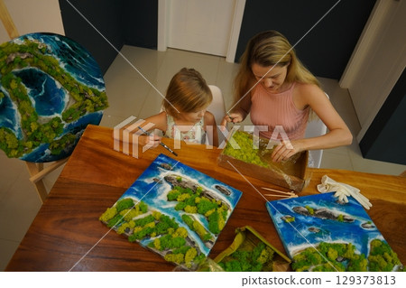 A mother and her daughter craft vibrant natural landscapes  129373813