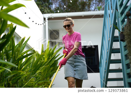 A woman raking the lawn at the backyard of her house A woman raking the lawn at the backyard of her house 129373861