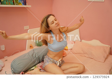 A young woman is enjoying a wonderfully serene morning in her bedroomnd A young woman is enjoying a wonderfully serene morning in her bedroomnd 129373924