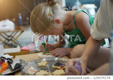 Mother and her daughter paint Halloween cookies Mother and her daughter paint Halloween cookies 129374179