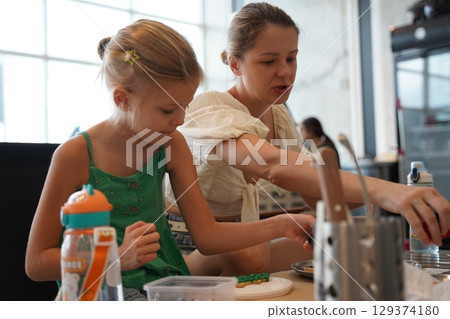 Mother and her daughter paint Halloween cookies Mother and her daughter paint Halloween cookies 129374180