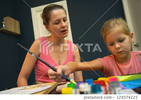 A mother and her young daughter engage in a colorful painting activity A mother and her young daughter engage in a colorful painting activity 129374225