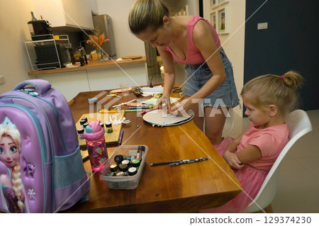 A mother and her young daughter engage in a colorful painting activity A mother and her young daughter engage in a colorful painting activity 129374230