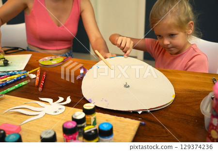 A mother and her young daughter engage in a colorful painting activity A mother and her young daughter engage in a colorful painting activity 129374236