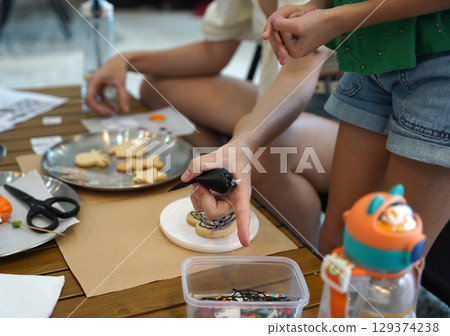Mother and her daughter paint Halloween cookies Mother and her daughter paint Halloween cookies 129374238