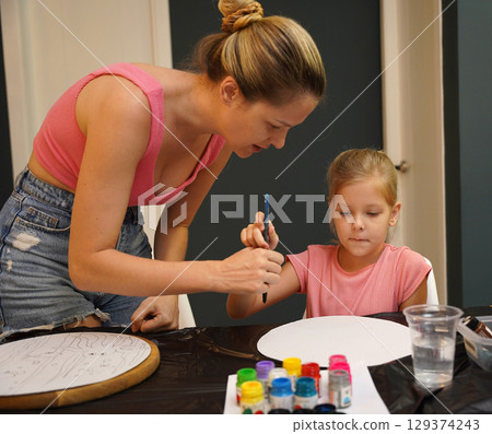 A mother and her young daughter engage in a colorful painting activity  129374243