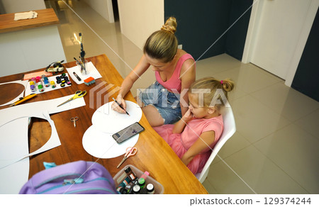 A mother and her young daughter engage in a colorful painting activity  129374244