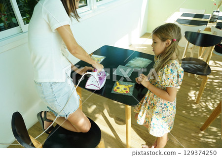 Teacher in workshop teched two girls how to assemble a thermo mosaic  129374250