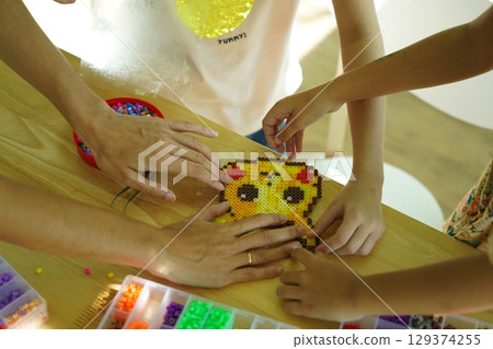 Teacher in workshop teched two girls how to assemble a thermo mosaic  129374255