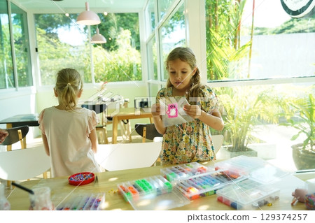 Teacher in workshop teched two girls how to assemble a thermo mosaic  129374257