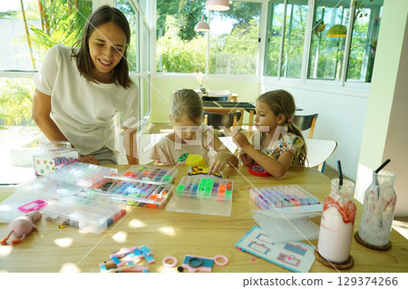 Teacher in workshop teched two girls how to assemble a thermo mosaic  129374266