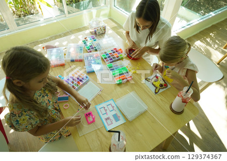 Teacher in workshop teched two girls how to assemble a thermo mosaic  129374367