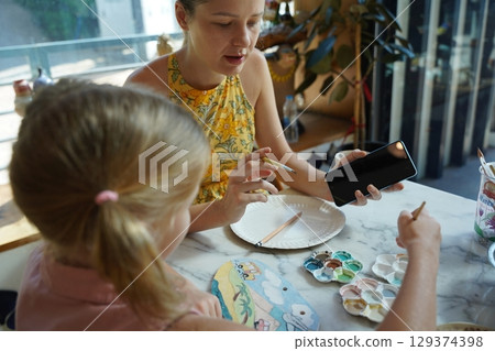 A young mother and her daughter enjoy a creative art session at home  129374398