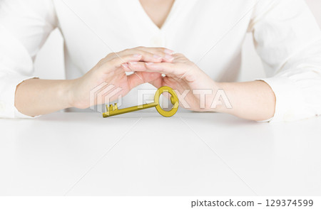 Hands Protecting Golden Key Symbolizing Opportunity and Security 129374599