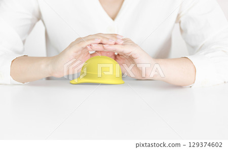 Protective Hands Above Yellow Hard Hat Representing Workplace Safety Protective Hands Above Yellow Hard Hat Representing Workplace Safety 129374602