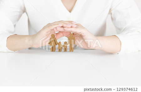 Hands Protecting Wooden Cutout Family Figures Symbolizing Parenthood and Family Insurance 129374612