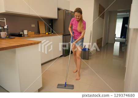 A woman is cleaning her living room at home 129374680